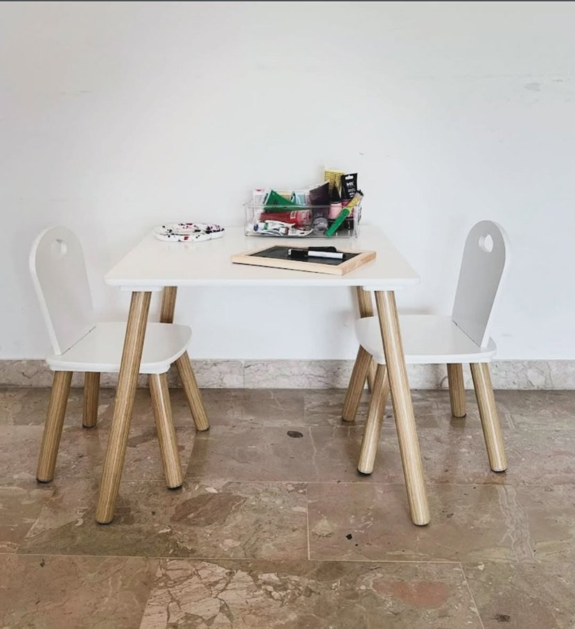 Angolo dello studio dedicato ai bambini: tavolino bianco, sedie in legno e materiali per il gioco